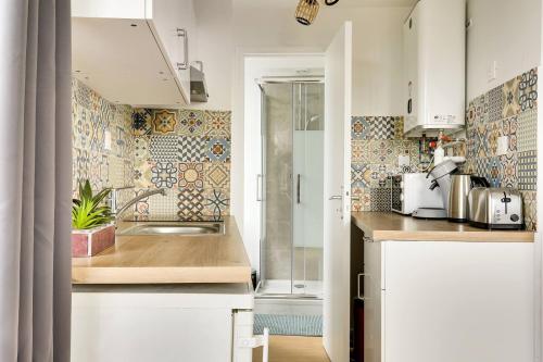 - une cuisine avec des placards blancs et un évier dans l'établissement Studio Au Bord du Canal (4B) *Paris*Disney*, à Chelles