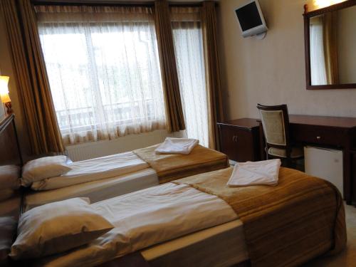 two beds in a hotel room with a window at Guest House Chicho Tsane in Bansko