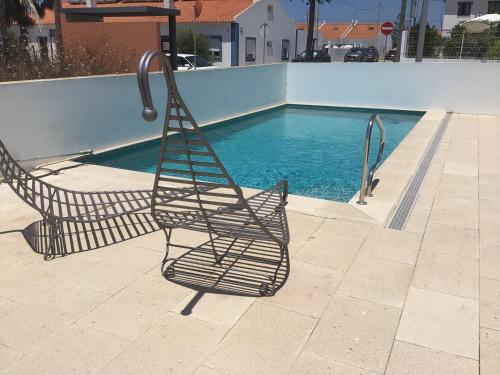 a metal chair sitting next to a swimming pool at Aivados in Porto Covo