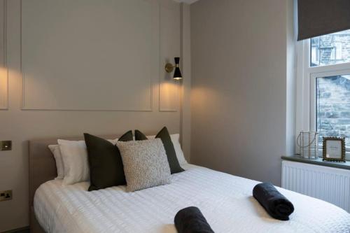 a bedroom with a large white bed with black pillows at The Verdant Apartment in Harrogate