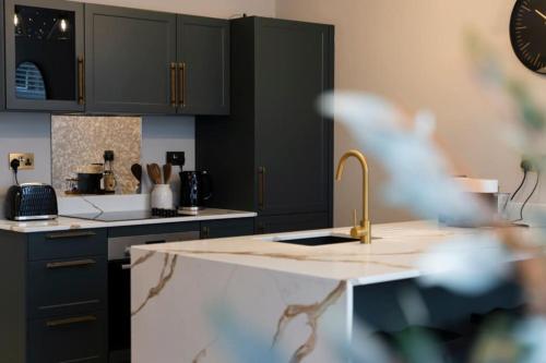 a kitchen with black cabinets and a sink at The Verdant Apartment in Harrogate