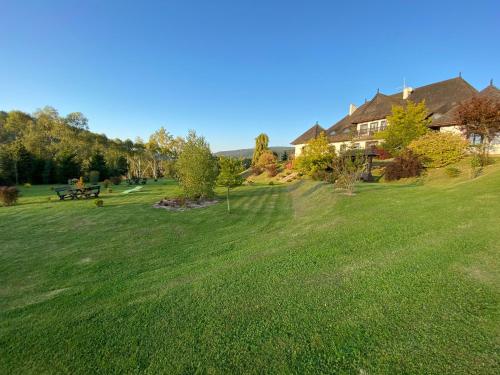 a large grassy field with a house in the background at Dwór na Wrzosowisku in Cisna