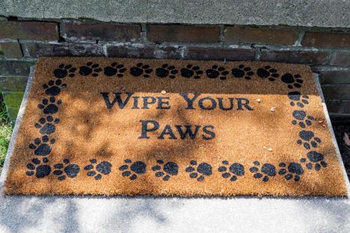 a sign that says wipe your paws on a brick wall at The Cooper Home, Dogs Welcome! in Ephrata