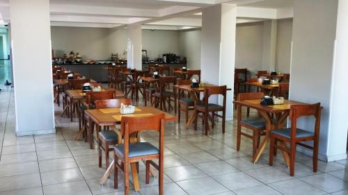 a dining room with wooden tables and chairs at Plaza Inn Trevo Sorocaba in Sorocaba