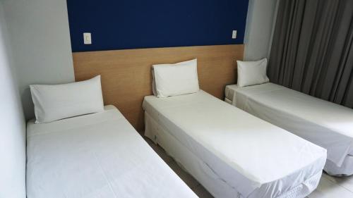 two beds in a room with white sheets and pillows at Plaza Inn Trevo Sorocaba in Sorocaba