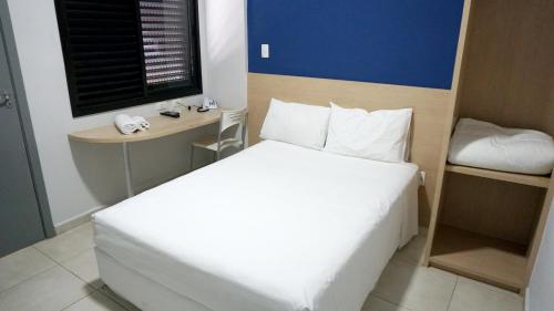a bedroom with a large white bed and a desk at Plaza Inn Trevo Sorocaba in Sorocaba