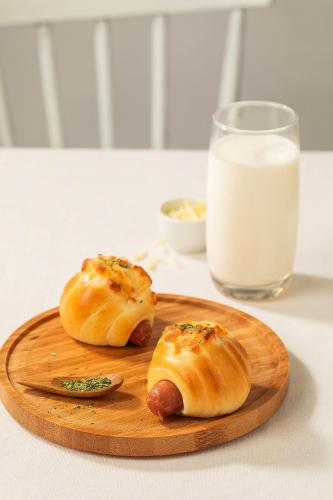 dois cachorros-quentes em uma tábua de corte com um copo de leite em 头等舱国际酒店-成都天府机场店 em Jianyang