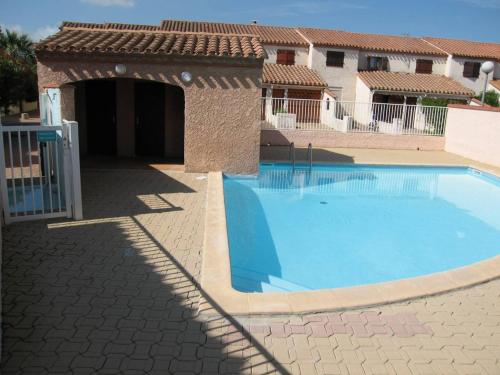 une grande piscine dans une cour avec un bâtiment dans l'établissement Villa 3 pièces climatisée avec jardin, proche plage, piscine, parking, et animaux autorisés - Saint Cyprien - FR-1-106-32, à Saint-Cyprien