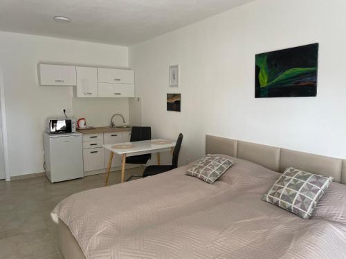 a bedroom with a bed and a table and a kitchen at Apartmány Silvia in Dunajská Streda