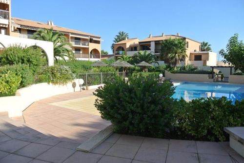 une cour avec une piscine et quelques bâtiments dans l'établissement Studio l Arbanais, à Hyères