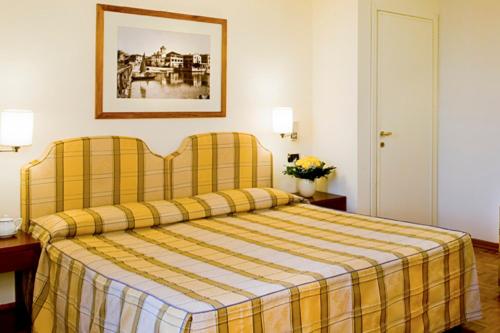 a hotel room with a bed with a yellow plaid blanket at Hotel Sirmione Terme in Sirmione
