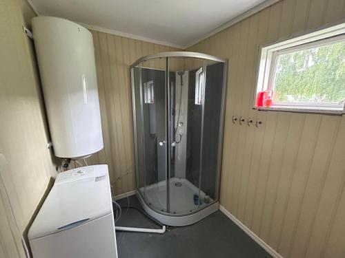 a small bathroom with a shower and a refrigerator at Hyra lantligt boende i Höga Kusten in Västhammar