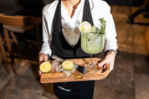 a woman holding a serving tray with a drink and lemon slices at Hotel Ramonda in Boljevac