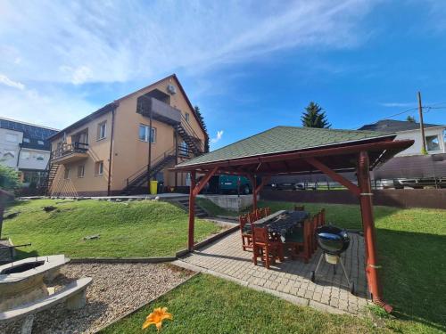 een paviljoen met een grill in een tuin bij Katalin Apartmanház in Miskolctapolca