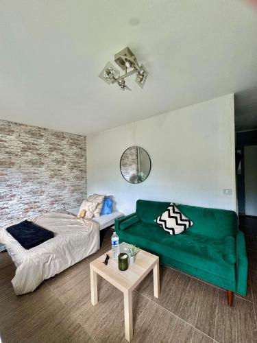 une chambre avec un lit et un canapé vert dans l'établissement Charmant studio à 7min de Paris, à Clichy