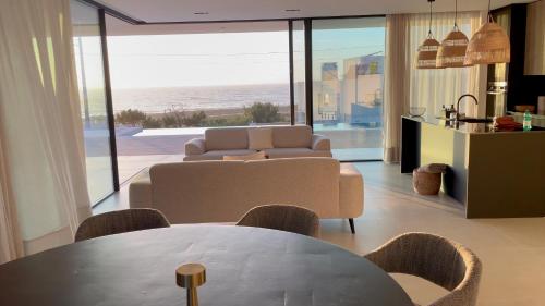 a living room with a table and a view of the ocean at Exclusive Beach House with full sea view, Luxury and Comfort by the Sea in Murtinheira