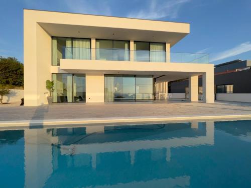 a house with a swimming pool in front of it at Exclusive Beach House with full sea view, Luxury and Comfort by the Sea in Murtinheira