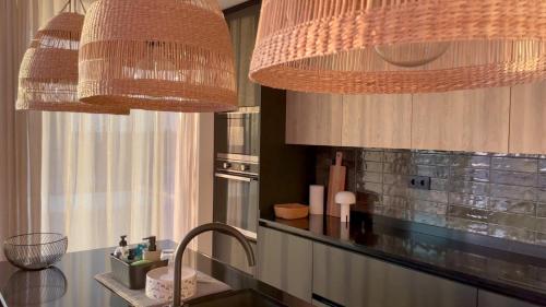 a kitchen with two chandeliers and a counter top at Exclusive Beach House with full sea view, Luxury and Comfort by the Sea in Murtinheira