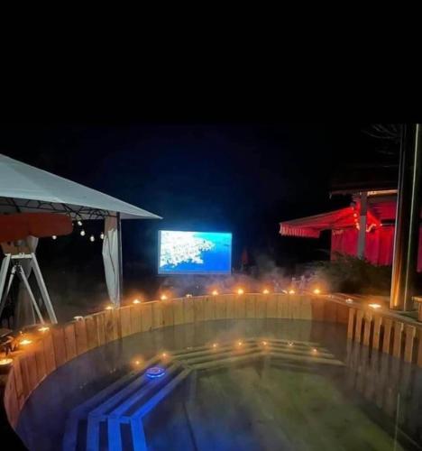 a swimming pool at night with a tv in the background at Cabana Casuta din Vis in Beclean
