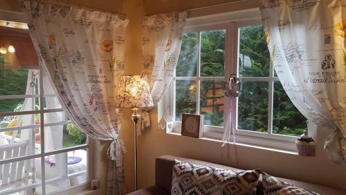 a room with a window with curtains and a couch at Cabana Casuta din Vis in Beclean