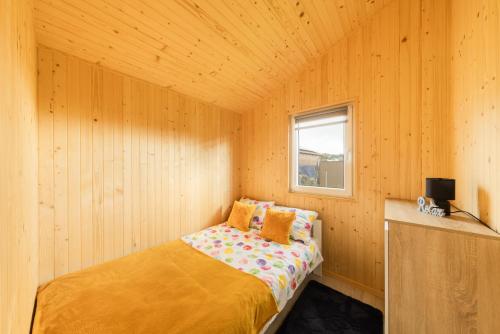 a small bedroom with a bed in a wooden room at Malinowe Zacisze - Domek żółty in Rusinowo