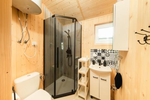 a bathroom with a shower and a toilet and a sink at Malinowe Zacisze - Domek żółty in Rusinowo
