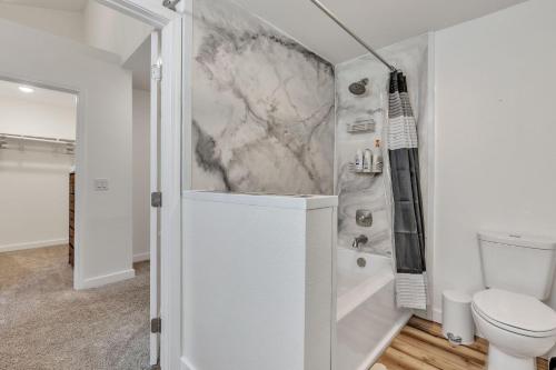 a white bathroom with a shower and a toilet at Apartment in Anchorage -10 Mi to Alaska Zoo! apts in Anchorage