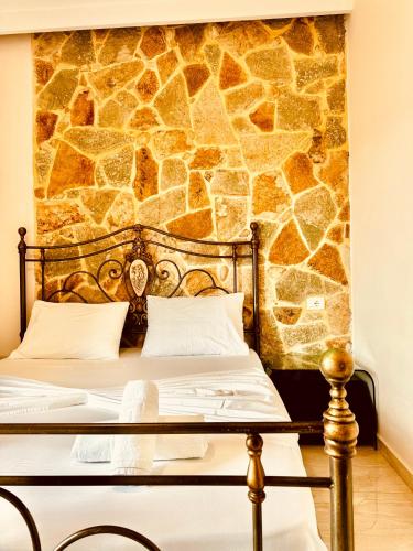 a bedroom with a stone wall behind a bed at Villa Merkuri in Himare