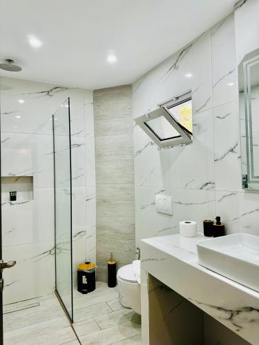a white bathroom with a sink and a toilet at Villa Merkuri in Himare