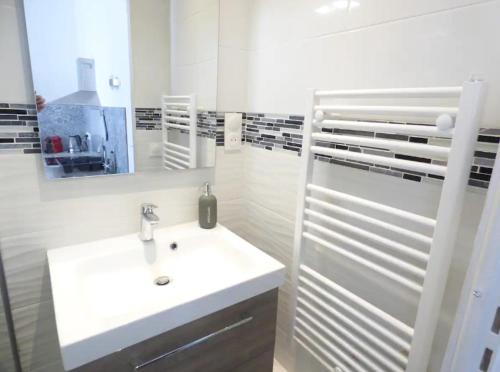 a white bathroom with a sink and a mirror at appartement 2 pièces Jean Macé et stationnement in Lyon