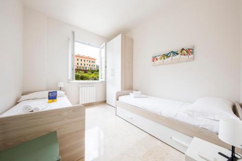 a white bedroom with two beds and a window at CasaViva - Quiet Trilo in Camogli in Camogli