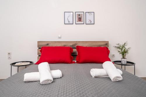 a bed with red pillows and white towels on it at Viola Apartment in Kissamos