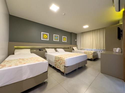 a hotel room with two beds and a television at Hotel Morada do Sol in Caldas Novas