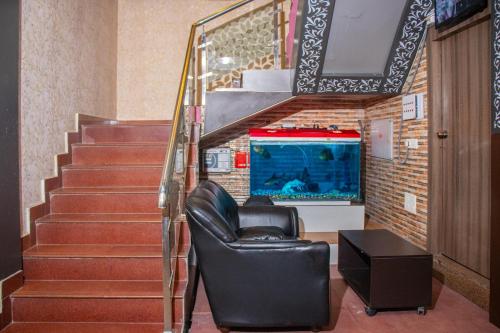 a room with a chair and stairs with a fish tank at Babul Hotel in Kolkata