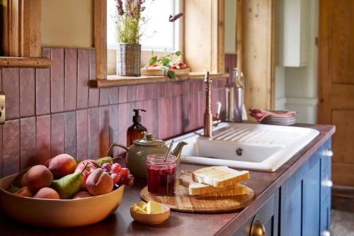 a kitchen counter with a bowl of fruit and a sink at 4 Coastguard Cottages - Porthgwarra in Porthcurno