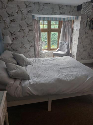 Un dormitorio con una cama y una silla y una ventana. en The Blue Bell, en Boroughbridge