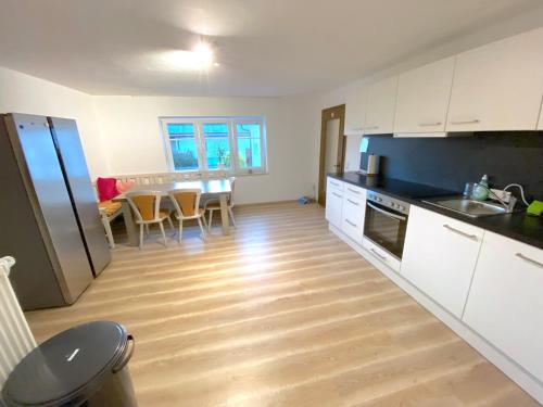 a kitchen with white cabinets and a table and chairs at IV Apartment 12 Personen - Monteurzimmer - Ferienwohnung - Kronwieden in Loiching