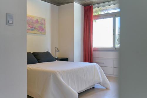 a bedroom with a white bed and a window at CINCO - Departamentos in La Plata