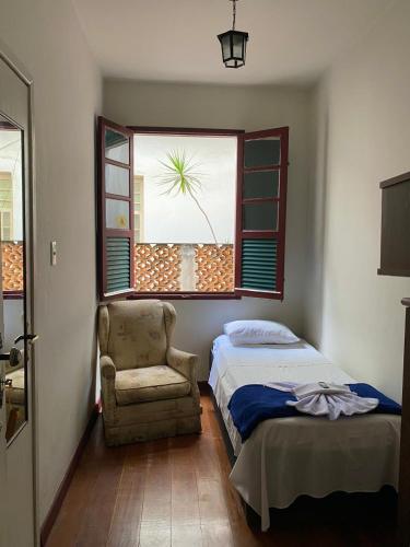 a bedroom with a bed and a chair and a window at Casa do Alferes in Ouro Preto