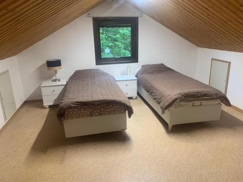 a attic bedroom with two beds and a window at Fint hus nära Hörby in Hörby