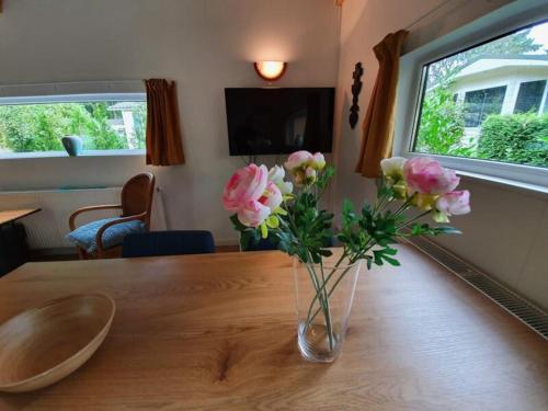 eine Vase rosafarbener Blumen auf einem Holztisch in der Unterkunft Comfortabele houten Chalet bij de Veluwe in Epe