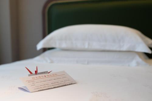 a white bed with a ticket on top of it at Nost algia S Hotel Shanghai Fudan University 时光漫步S酒店上海复旦大学五角场地铁站店 Free fresh ground coffee,Free laundry service in Shanghai