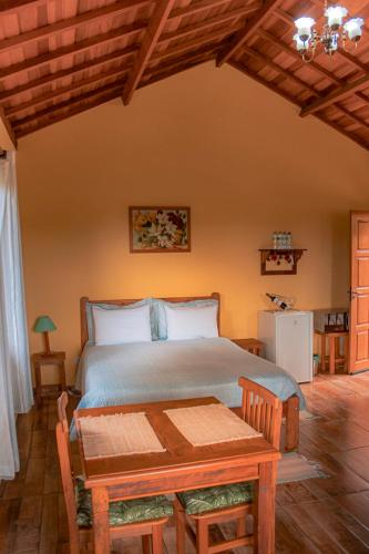a bedroom with a bed with a wooden table and a table sidx sidx at Pousada Canto dos Pássaros in Santo Antônio do Pinhal