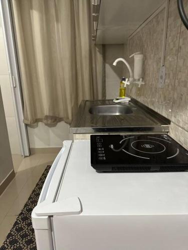 a white kitchen with a sink and a stove at Kitnet 301 centro linda vista por sol com tv smart e ar in Montes Claros