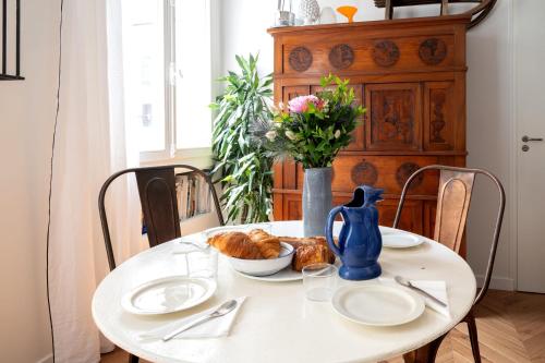 une table blanche avec des assiettes et un vase de fleurs dans l'établissement Appartement Ottomane - Welkeys, à Paris