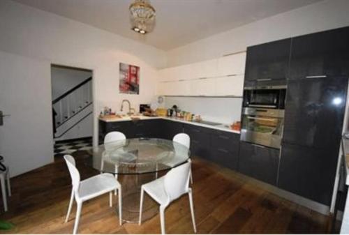 une cuisine avec une table en verre et des chaises blanches dans l'établissement Villa Joia Molitor - Roland Garros, à Boulogne-Billancourt