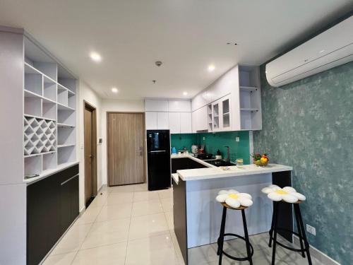 a kitchen with white and green walls and stools at Căn hộ 1PN 2 giường Vin Grand Park chỉ từ 550k in Gò Công