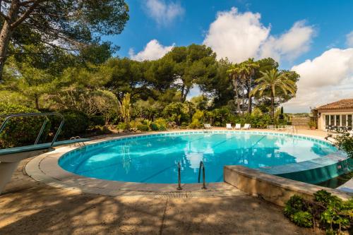 une grande piscine avec des arbres en arrière-plan dans l'établissement Le Clochet du Cap D'Antibes Pavillion de 690m2 Tennis Piscine Spa Plage, à Juan-les-Pins