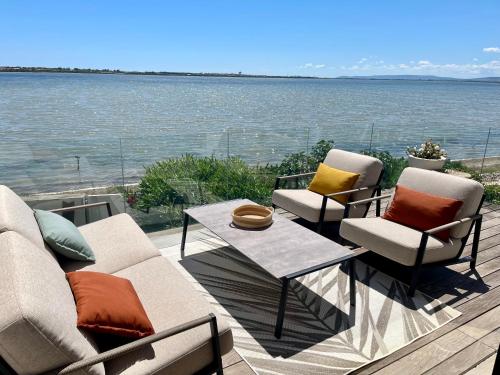 d'une terrasse avec des chaises, une table et l'eau. dans l'établissement Design villa with panoramic pond view and jacuzzi, à Pérols