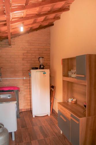 a kitchen with a white refrigerator in a room at Pousada Canto dos Pássaros in Santo Antônio do Pinhal